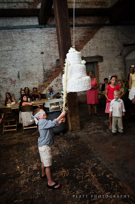 child swinging at the wedding cake piñata at the wedding reception